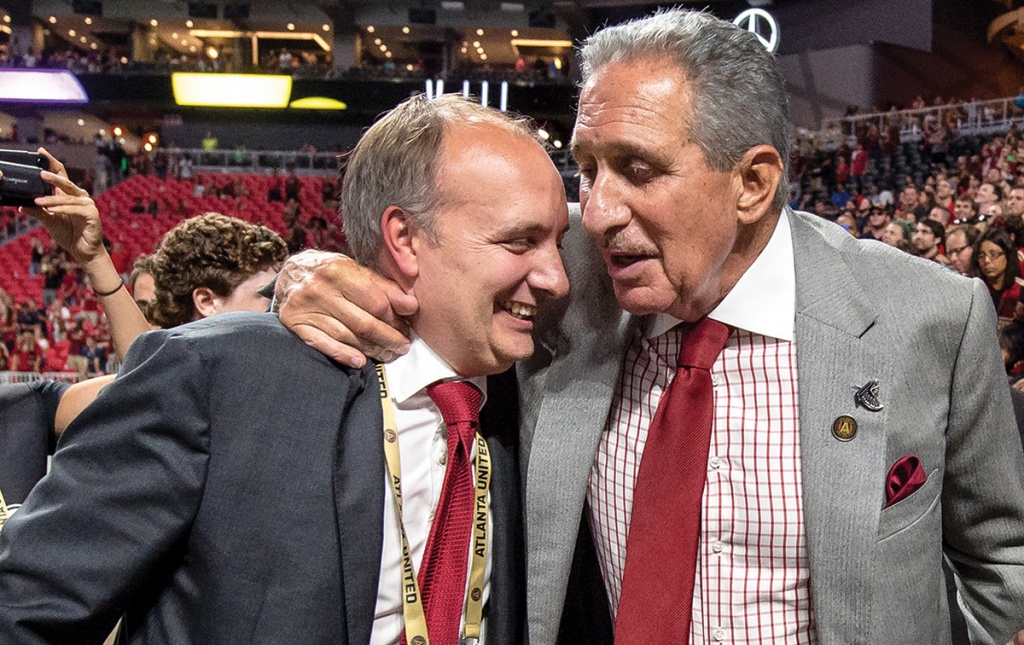 Photograph of Darren Eales &rsquo;95 hugging Falcons and Atlanta United owner Arthur Blank in a stadium